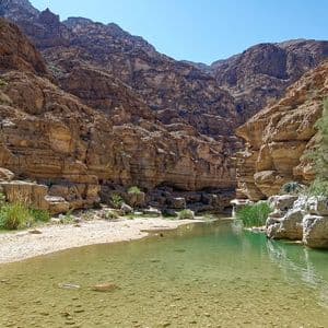 Un fiume poco profondo con acqua verde chiara scorre attraverso un ripido canyon roccioso in una giornata di sole