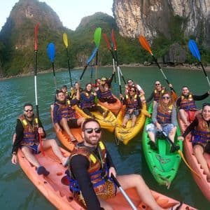 Eine WeRoad-Gruppe macht ein Selfie beim Kajakfahren auf dem Wasser zwischen großen Felsformationen.