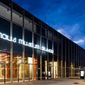 La moderna facciata in vetro del Bauhaus Museum Dessau illuminata di notte, con la sua insegna al neon che brilla contro un cielo blu scuro.