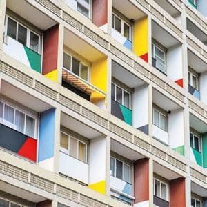 La facciata di un moderno edificio residenziale con una griglia di balconi in cemento dipinti con colori primari vivaci.