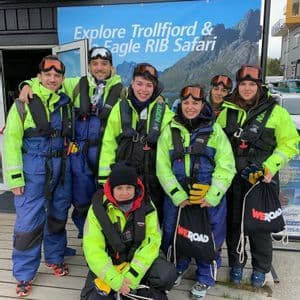 A WeRoad group trip poses for a photo in waterproof gear and life vests before a boat safari.