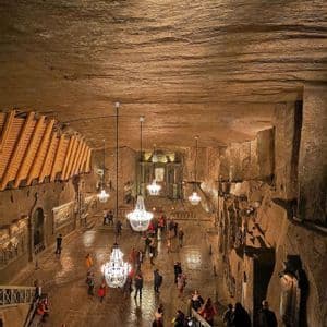 Un viaje en grupo de WeRoad visita una vasta catedral subterránea tallada en la roca, iluminada por grandes candelabros de cristal, vista desde arriba.
