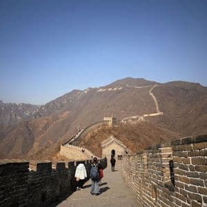 Un viaggio di gruppo WeRoad a piedi lungo un muro di pietra che serpeggia tra montagne brulle sotto un cielo azzurro limpido.