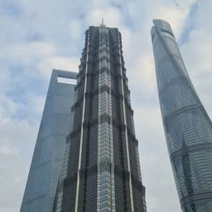 Una vista dal basso di tre moderni grattacieli di vetro che si ergono verso un cielo parzialmente nuvoloso