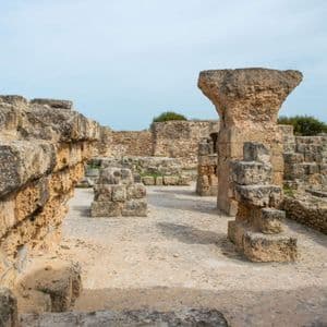 Antiguas ruinas de piedra con muros desmoronados y la base de una gran columna en un sitio arqueológico