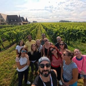 Un gruppo WeRoad si scatta un selfie in un grande vigneto con un castello sullo sfondo.