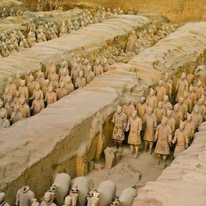 File di statue di guerrieri di terracotta a grandezza naturale schierate in formazione all'interno di grandi fosse di terra scavate.