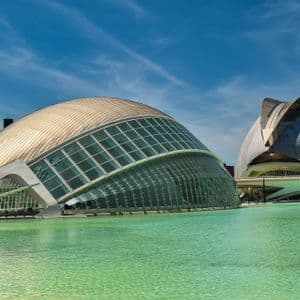 Due edifici futuristici a forma di cupola con facciate in vetro si trovano accanto a una piscina turchese sotto un cielo azzurro.