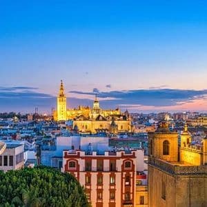 Città al crepuscolo con cattedrale e palazzi storici illuminati.