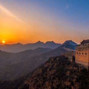 Vibranti terrazze di riso verdi su dolci colline con il sole che tramonta dietro montagne lontane sotto un cielo crepuscolare
