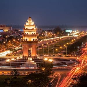 Un monumento iluminado en una rotonda de la ciudad por la noche, capturado con una exposición larga para mostrar estelas de luces de tráfico.