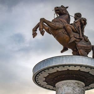 Una ripresa dal basso di una grande statua equestre in bronzo su un piedistallo circolare, con il cavallo che si impenna contro un cielo nuvoloso.
