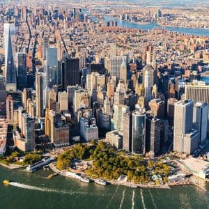 Vista aerea dello skyline di Lower Manhattan, con densi grattacieli circondati dai fiumi in una giornata di sole.