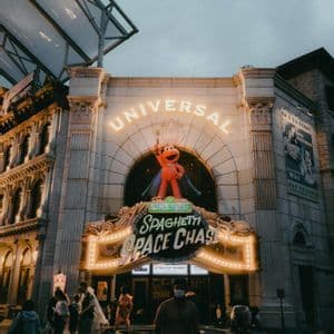 Der beleuchtete Eingang zur Universal-Attraktion 'Sesamstraße Spaghetti Space Chase', mit Passanten bei Einbruch der Dunkelheit.