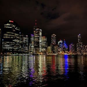 Un horizon urbain moderne illuminé la nuit, avec les lumières des bâtiments se reflétant sur la surface de l'eau.
