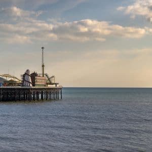 Un pontile divertimenti con varie attrazioni si estende sul mare calmo sotto un cielo parzialmente nuvoloso.