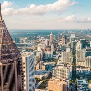Una vista aerea dello skyline di una vasta città, con un alto edificio e la sua caratteristica guglia prominenti in primo piano.