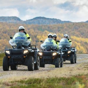 Un viaggio di gruppo WeRoad in quad, in fila su un sentiero sterrato attraverso un paesaggio collinare autunnale.