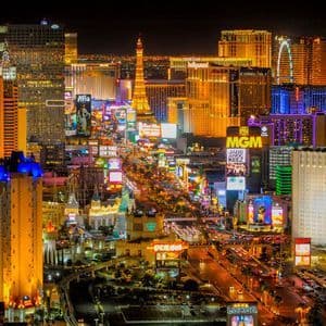 Vista aerea notturna di una trafficata strada cittadina, con grattacieli e hotel splendidamente illuminati da insegne e luci al neon colorate.