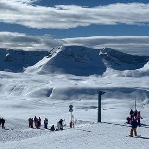 Un gruppo WeRoad si riunisce su una pista da sci innevata, con vaste montagne coperte di neve che si estendono all'orizzonte.