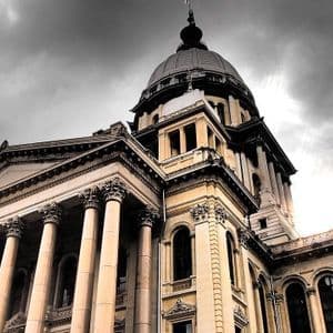 Un edificio clásico con una gran cúpula y columnas, en contrapicado, contra un cielo oscuro y nublado.