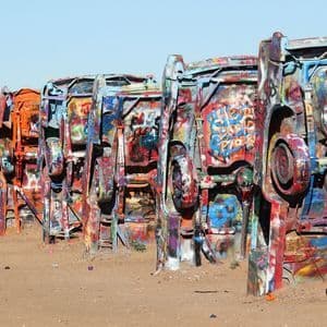 Una hilera de coches están enterrados de morro en la tierra, con sus bajos cubiertos de coloridas capas de grafitis.