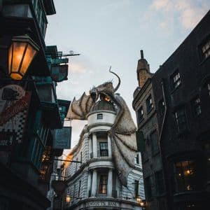 Una grande statua di drago è posizionata sul tetto a cupola dell'edificio della Banca Gringotts, ripresa dal basso.