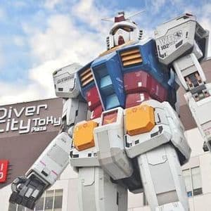 Uno scatto dal basso della statua gigante del robot Gundam di fronte all'edificio DiverCity Tokyo Plaza, sotto un cielo parzialmente nuvoloso.