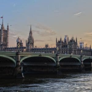 Una veduta del Palazzo del Parlamento e della torre dell'orologio del Big Ben dal Tamigi, con il Ponte di Westminster in primo piano al crepuscolo.