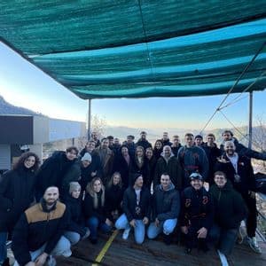 Un gruppo WeRoad in viaggio posa per una foto di gruppo su una piattaforma esterna con colline sullo sfondo.