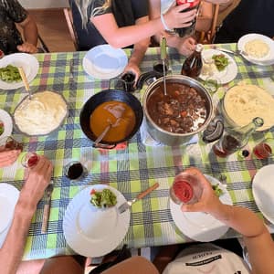 Vista dall'alto di un gruppo WeRoad che condivide un pasto attorno a un tavolo, con pentole di stufato e purè di patate.