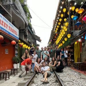 Un viaggio di gruppo WeRoad posa per una foto sui binari del treno che attraversano una strada stretta decorata con lanterne.