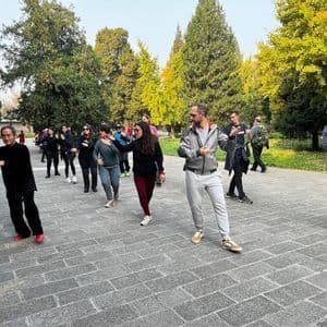 Un viaggio di gruppo WeRoad partecipa a una lezione di Tai Chi all'aperto con un istruttore in un parco.