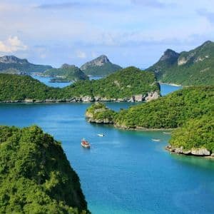 Una vista aerea di un arcipelago con isole verdi e lussureggianti, acqua blu calma e diverse piccole barche che navigano.