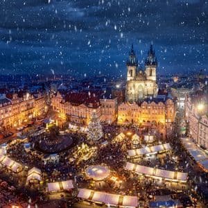 Vue aérienne d'un marché de Noël bondé sur une place historique, la nuit sous la neige.