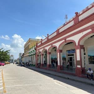 Una vista de la calle de edificios coloniales coloridos con largos soportales cubiertos bajo un cielo azul brillante.