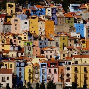 Un fitto insieme di case colorate con tetti rossi che ricopre una collina soleggiata.