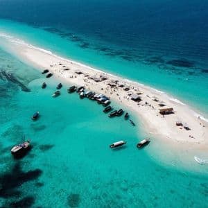 Vista aerea di un banco di sabbia bianca immerso in un mare turchese, con un gruppo WeRoad e numerose imbarcazioni radunate.