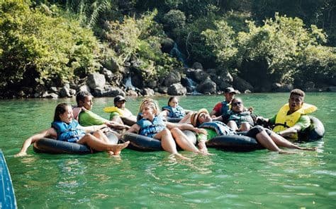 Un viaggio di gruppo WeRoad si rilassa su gommoni galleggiando lungo un fiume tranquillo, circondato da una riva lussureggiante e rocciosa.