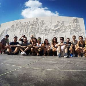 Eine WeRoad-Gruppe posiert für ein Foto vor einem großen, weißen Denkmal unter blauem Himmel.