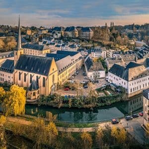 Una vista dall'alto di un quartiere storico di una città europea con una chiesa e altri edifici che costeggiano un fiume sinuoso durante l'autunno.