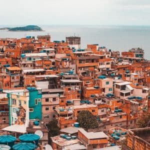 Edifici in mattoni arancioni fitti, con serbatoi d'acqua blu, su un fianco di collina che domina l'oceano e isole lontane.