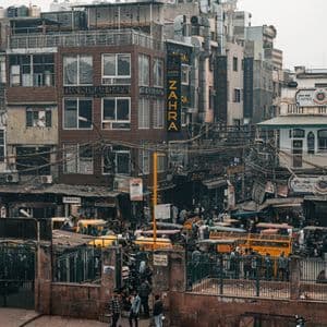 Una vista dall'alto di una strada cittadina brulicante di pedoni, tuk-tuk gialli e fitti edifici consumati dal tempo.