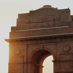 Un primer plano de un monumento de arco de piedra con la palabra INDIA tallada en la parte superior, iluminado por la luz del sol de la hora dorada.