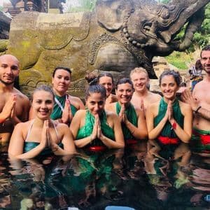 A WeRoad group trip posing with hands together in a sacred pool in front of a large, carved stone elephant.