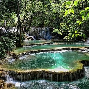 Une cascade en terrasses aux eaux turquoise éclatantes, se déversant dans des piscines naturelles au sein d'une jungle luxuriante et verdoyante.