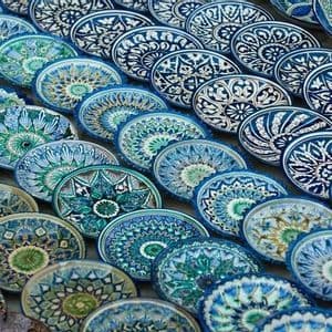 Des dizaines d'assiettes en céramique peintes à la main avec des motifs géométriques complexes bleus et verts sont exposées en rangées superposées.