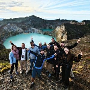 Eine WeRoad-Gruppenreise posiert für ein Foto auf einem Berggrat mit zwei türkisfarbenen Kraterseen im Hintergrund.