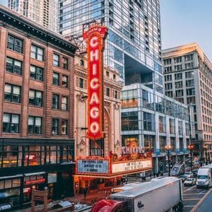 L'iconica insegna verticale del Chicago Theatre illuminata su una trafficata strada cittadina con traffico e moderni grattacieli