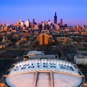 Una vista aerea del tetto a cupola dello United Center con lo skyline di Chicago visibile sullo sfondo contro un cielo crepuscolare.
